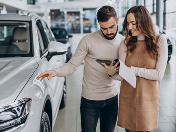 Frau zeigt Mann ein Autoverkauf Angebot auf dem Tablet bei Autoankauf Hilden